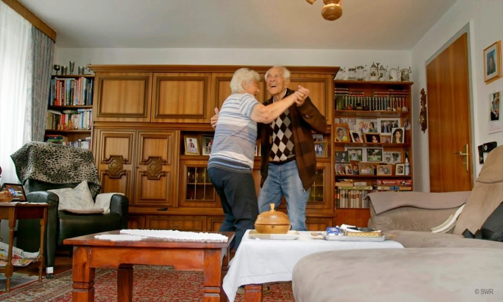 Filmstill: Alexa bitte einen Walzer spielen - älteres Paar tanzt im Wohnzimmer (© SWR)